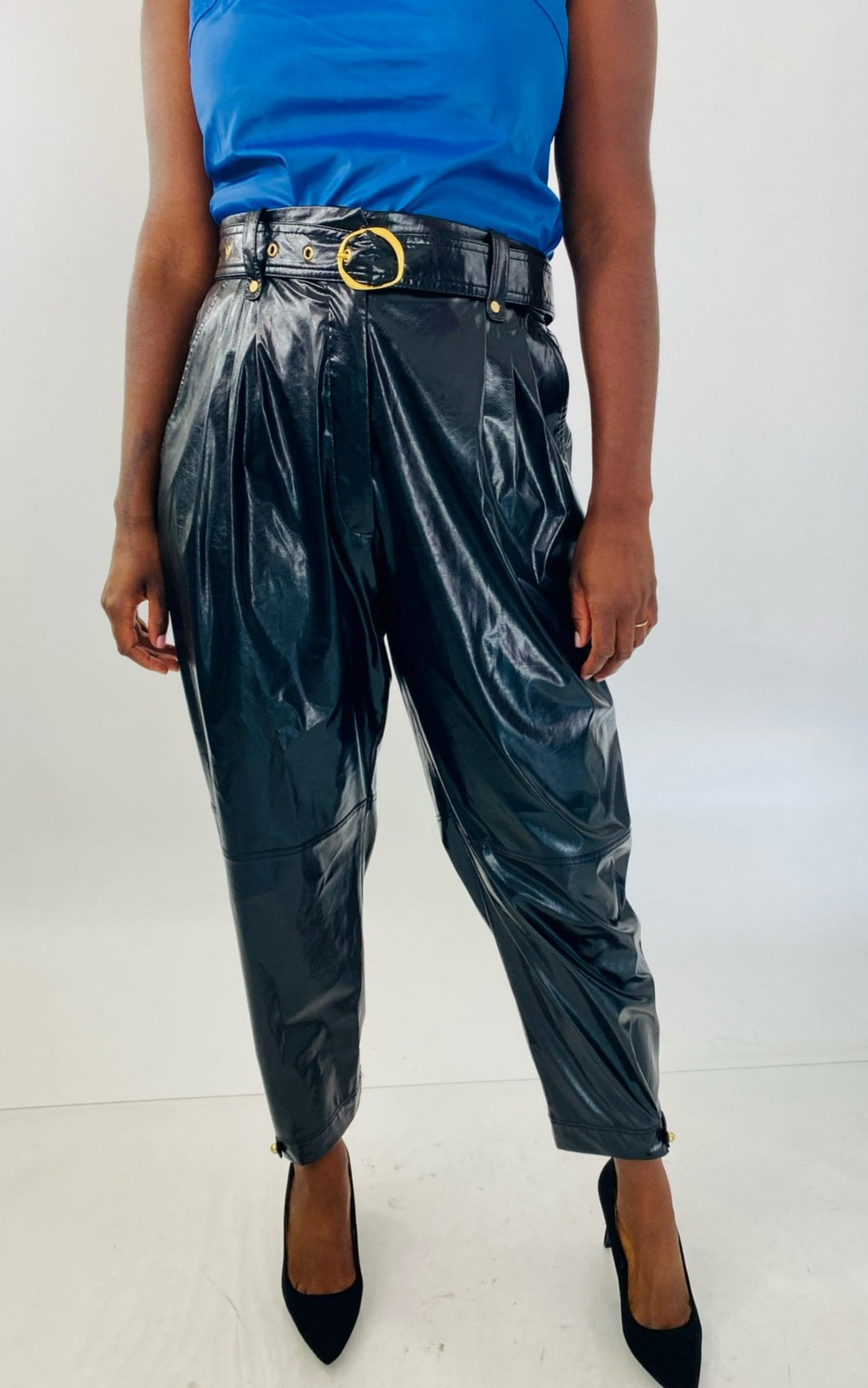 Front view of these sexy size 14 Tanya Taylor black pleather high waisted tapered trousers with belt and gold hardware styled with a blue pleather tank and black pumps on a size 12 model.