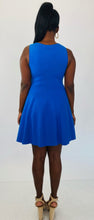 Load image into Gallery viewer, Back view of a size 14/16 Milly for 11Honoré cobalt blue a-line sleeveless mini dress with twisted neckline styled with tan suede strappy heels on a size 12 model.
