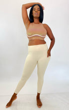 Load image into Gallery viewer, Full-body front view of a size L Fabletics brown high-neck active crop top with rainbow metallic shift styled with cream colored leggings on a size 12 model.

