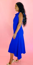 Load image into Gallery viewer, Full-body side view of a size 16 Reem Acra for 11 Honoré cobalt blue subtle cowl neck sleeveless maxi with handkerchief hem styled with tan patent leather heels on a size 10/12 model.
