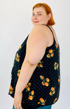 Load image into Gallery viewer, Side view of a size 4 Torrid black flowy tank top with an orange pattern and white mini polka dots on a size 22 model. The straps are adjustable.
