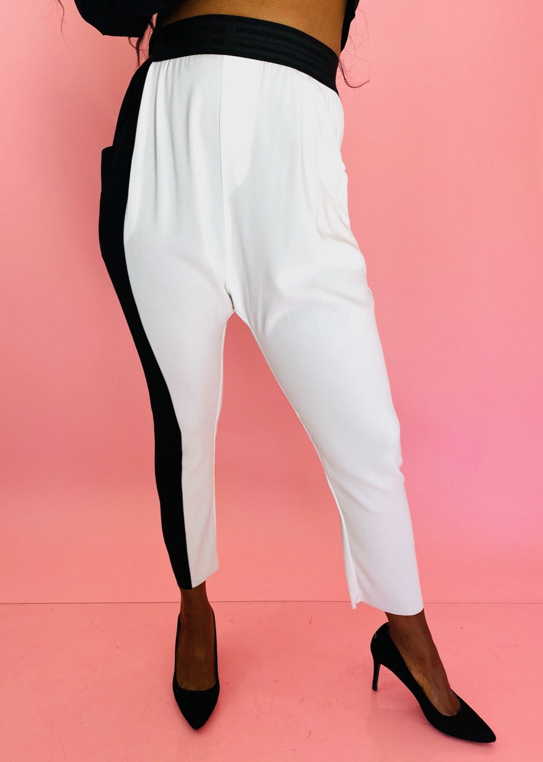 Front view of a pair of size 3 Baja East for 11 Honoré crisp white drop-crotch tapered pants with a black side stripe and elastic waistband styled with black pumps on a size 12 model.