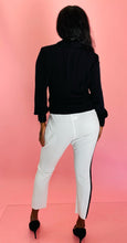 Load image into Gallery viewer, Full-body back view of a pair of size 3 Baja East for 11 Honoré crisp white drop-crotch tapered pants with a black side stripe and elastic waistband styled with a black blouse and black pumps on a size 12 model.

