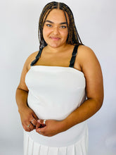 Load image into Gallery viewer, Closer view of a bodice and faux leather straps of a size 16 Jamie Wei Huang white asymmetrical hem midi dress with pleated skirt, pocket details, and faux leather straps on a size 18/20 model.
