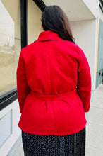 Load image into Gallery viewer, Back view of a size 14 Bloomchic deep red felt collared coat with belt styled closed over a black and white polka dot maxi dress on a size 14/16 model.
