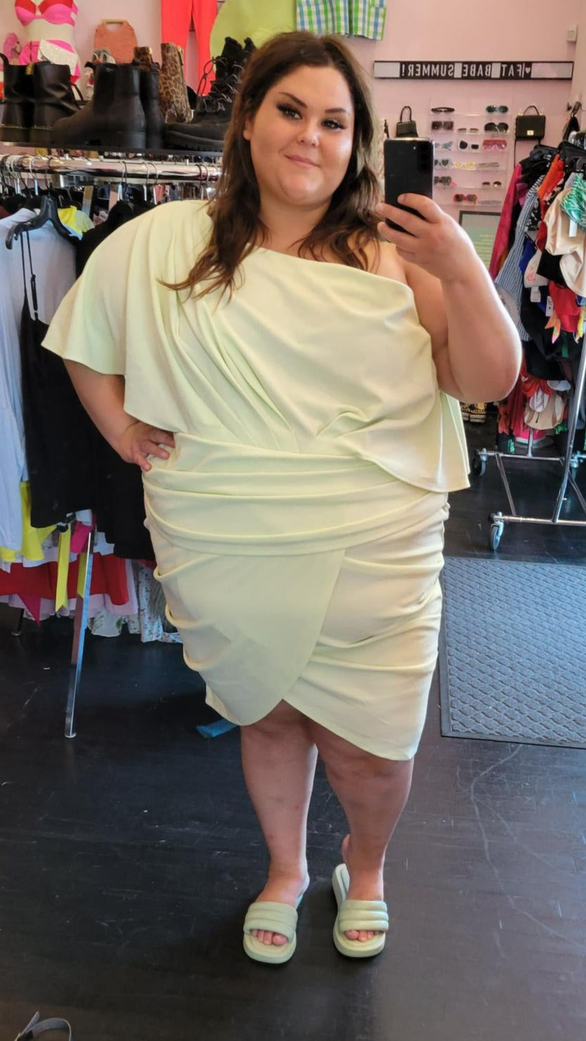 Full-body front view of a size 4 Fashion to Figure x Nadia mint green draped midi dress styled with mint green slides on a size 22/24 model.