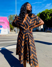 Load image into Gallery viewer, A sunny, outdoors shot of a size 12 model wearing a size 14 Maria Cornejo for 11 Honoré black and rust orange chevron patterned v-neck a-line maxi dress. The sunlight really brings out the vibrancy of the orange against the black chevrons!
