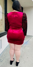 Load image into Gallery viewer, Full-body back view of a red velvet bodycon mini dress with black velvet puff sleeves with red sequins styled with black heels on a size 14/16 model.
