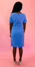 Load image into Gallery viewer, Full-body back view of a size 16 Zac Posen for 11 Honoré periwinkle blue v-neck short sleeve midi dress with pleated pattern styled with white heels on a size 10/12 model.
