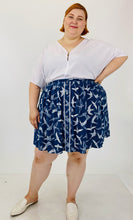 Load image into Gallery viewer, Front view of the size 3 Fashion to Figure x Sarah Rae Vargas crisp white wide-sleeved bodysuit with stretch at the bottom styled with a navy blue and white circle skirt and white slides, on a size 22 model.
