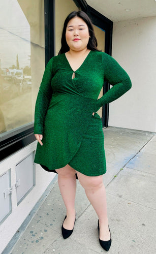 Full-body front view of a size 16 Bloomchic emerald green shimmer blackground dress with long sleeves and tulip hem on a size 14/16 model.