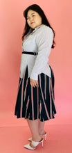Load image into Gallery viewer, Full-body side view of a size L TOME for 11 Honoré white, green, blue, red, and black mixed pinstripe and triple stripe collared button-up shirt dress with tie belt styled with white heels on a size 14/16 model.
