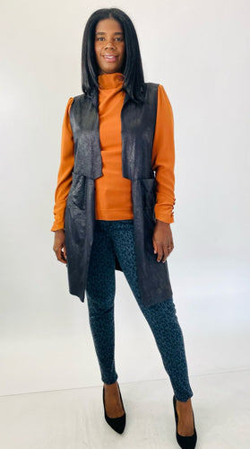 Full-body front view of this size L Gershon Bram black faux suede duster vest styled over an orange turtlneck blouse, gray leopard print pants, and black pumps on a size 12 model.