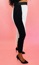 Load image into Gallery viewer, Side view of a pair of size 3 Baja East for 11 Honoré crisp white drop-crotch tapered pants with a black side stripe and elastic waistband styled with black pumps on a size 12 model.
