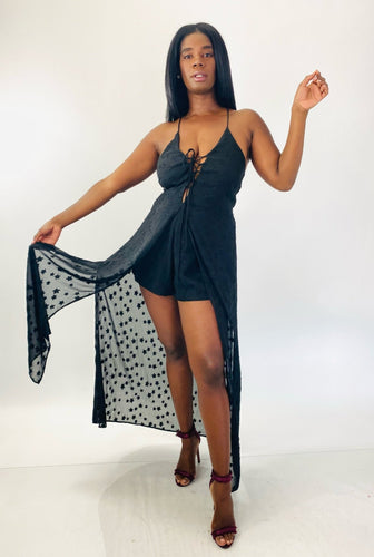 Full-body front view of a stunning size 14 Showpo. black lace-up criss-cross detail shorts romper with star-printed sheer black mesh maxi overlay styled with maroon strappy heels on a size 12 model.