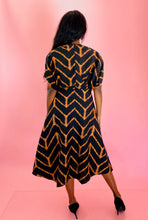 Load image into Gallery viewer, Full-body back view of a size 14 Maria Cornejo for 11 Honoré black and rust orange chevron patterned v-neck a-line maxi dress styled with black pumps on a size 12 model.
