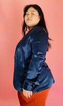 Load image into Gallery viewer, Side view of a size 3 Baja East for 11 Honoré deep blue satin blazer with hook and eye closure and subtle puff sleeves styled with a white tee and rust orange silky pants on a size 14/16 model.
