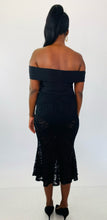 Load image into Gallery viewer, Full-body back view of this Fashion to Figure size 1 off-the-shoulder black bodysuit maxi dress with black lace overlay and mermaid-style skirt styled with black heels on a size 12 model.
