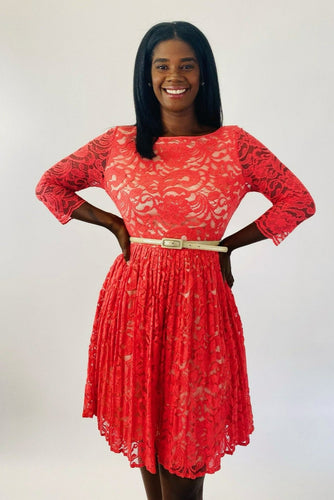 Front view of a size 16 Eliza J coral lace long sleeve pleated midi dress with cream lining underneath and cream skinny belt on a size 12 model.