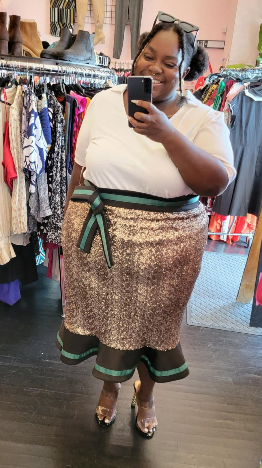 Full-body front view of a size 26 Eloquii gold sequin maxi skirt with black and green ruffle hem and waist detail styled with a white collared shirt and heels on a size 22/24 model.