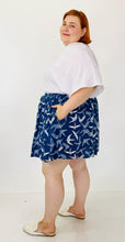 Load image into Gallery viewer, Side view of the size 3 Fashion to Figure x Sarah Rae Vargas crisp white wide-sleeved bodysuit with stretch at the bottom styled with a navy blue and white circle skirt and white slides, on a size 22 model.
