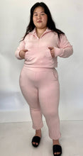 Load image into Gallery viewer, Full-body front view of a size 1 11 Honoré baby pink two-piece lounge set sold as is with some pen marks styled with black slides on a size 14/16 model.
