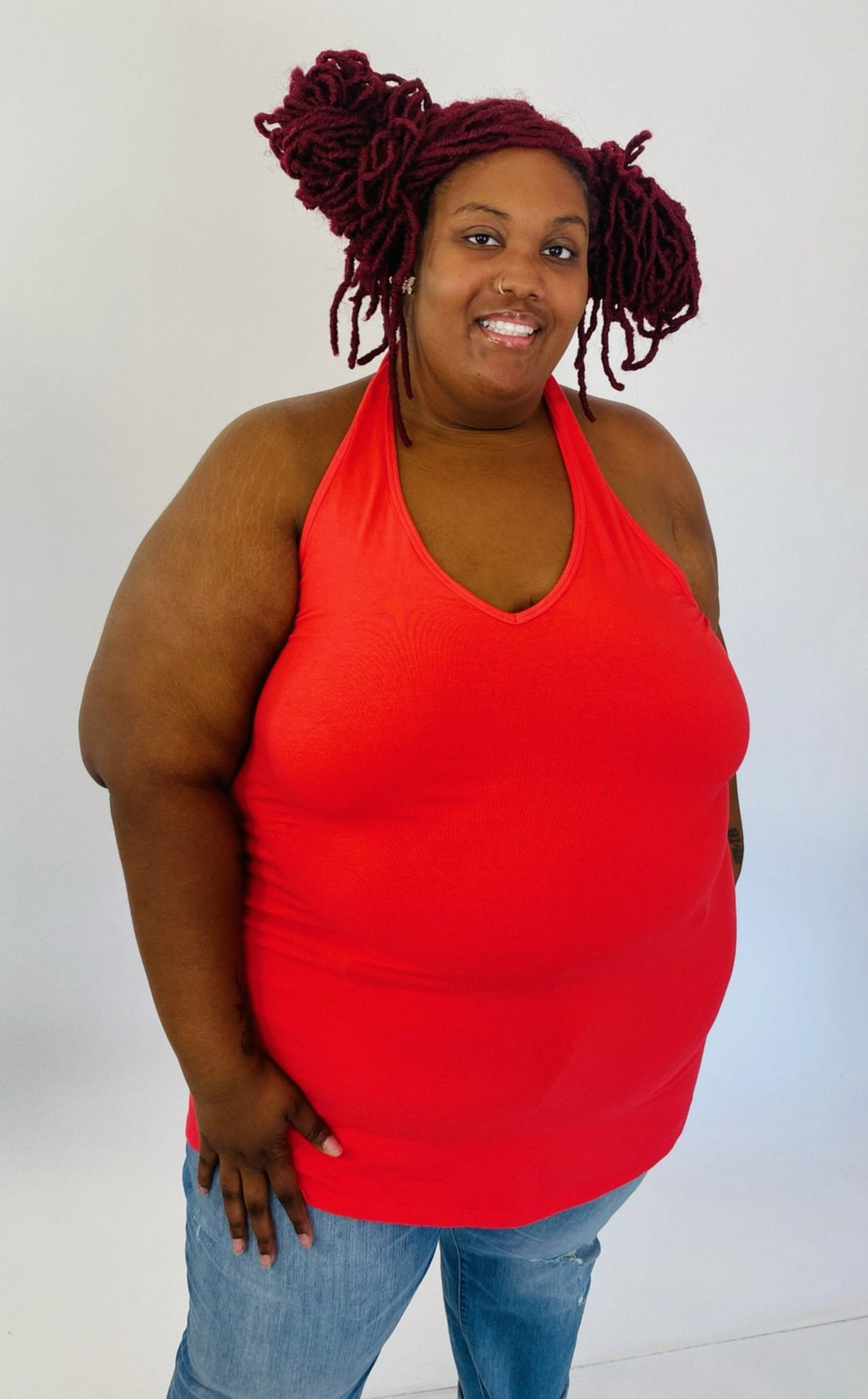Front view of a size 6 Torrid coral red v-neck halter tank styled with light wash jeans on a size 26/28 model.