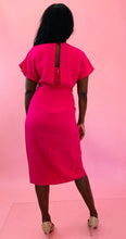Load image into Gallery viewer, Full-body back view of a size 12 hot pink sheath dress with knotted torso detail, flutter sleeves, and fabric buttons at the hem styled with tan pumps on a size 10/12 model.
