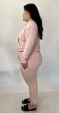 Load image into Gallery viewer, Full-body side view of a size 1 11 Honoré baby pink two-piece lounge set sold as is with some pen marks styled with black slides on a size 14/16 model.
