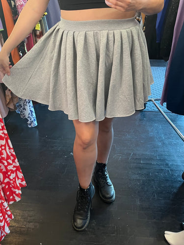 Front view of a size 14 Pretty Little Thing gray sweatshirt circle skirt styled with black combat boots on a size 14/16 model.