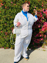 Load image into Gallery viewer, Additional full-body front view of a size 5X Big Bud Press off-white collared boiler suit/jumpsuit with zip-front details styled over a blue turtleneck and blue boots on a size 22 model in front of a flowering bush.

