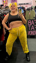 Load image into Gallery viewer, Full-body front view of a size XL Urban Outfitters mustard yellow ribbed corduroy pants with embroidered peace signs styled with a black crop and black combat boots on a size 16/18 model.
