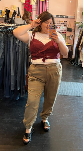 Full-body front view of a size 16 Eloquii white tee with connected maroon wrap tank detail styled with tan plaid pants and black slides on a size 14/16 model.