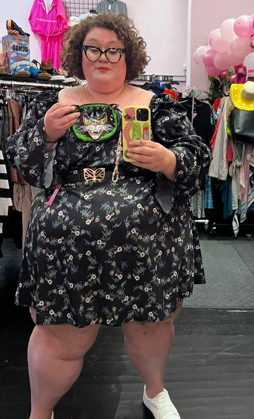 Full-body front view of a size 26 ASOS black mini dress with white, blue, and pink mini floral pattern all throughout styled with a black butterfly belt on a size 26 model.