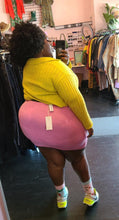 Load image into Gallery viewer, Full-body back view of a size XL Lezé the Label stretchy bubblegum pink mini skirt styled with a yellow sweater crop and neon sneakers on a size 22/24 model.
