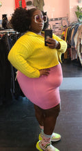 Load image into Gallery viewer, Full-body side view of a size XL Lezé the Label stretchy bubblegum pink mini skirt styled with a yellow sweater crop and neon sneakers on a size 22/24 model.
