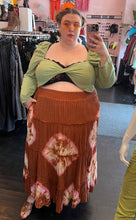 Load image into Gallery viewer, Full-body front view of a size 26 Pretty Little Thing sage green crop top with twist-bust detail and puff shoulders and sleeves styled with a rust brown skirt and orange sunglasses on a size 24 model.
