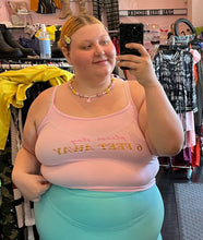 Load image into Gallery viewer, Front view of a size XL French Affair baby pink &quot;Please Stay 6 Feet Away&quot; graphic cropped tank styled with a blue mini skirt on a size 22/24 model.
