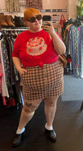 Load image into Gallery viewer, Full-body front view of a size 24W Wild Fable peach, red, and brown plaid mini skirt with zip up detail styled with a red graphic tee on a size 22/24 model.
