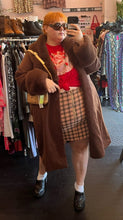 Load image into Gallery viewer, Full-body front view of a size 24W Wild Fable peach, red, and brown plaid mini skirt with zip up detail styled with a red graphic tee under a brown fur coat on a size 22/24 model.
