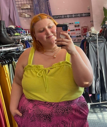 Close up view of a size XL Free Assembly chartreuse ribbed, textured tank with ruffled bust and tie bust detail styled with gold jewelry and pink and black mixed animal print pants on a size 22/24 model.