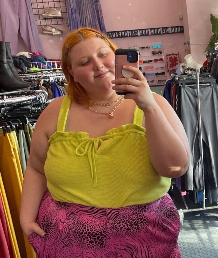 Close up view of a size XL Free Assembly chartreuse ribbed, textured tank with ruffled bust and tie bust detail styled with gold jewelry and pink and black mixed animal print pants on a size 22/24 model.