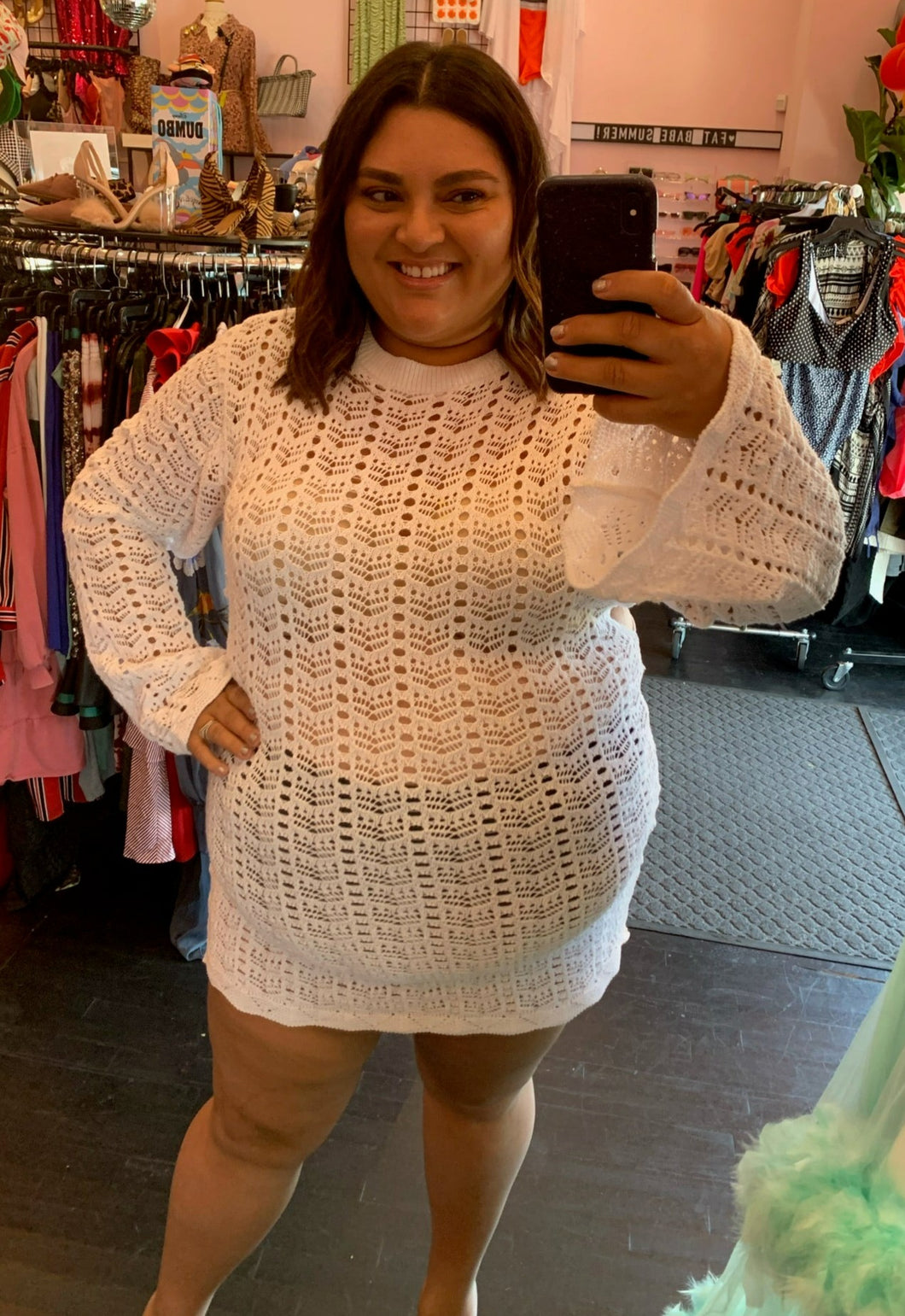 Front view of a size 24 Pretty Little Thing white crochet mini dress with bell sleeves on a size 18/20 model.