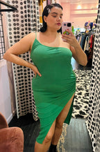 Load image into Gallery viewer, Closer front view of a size 14 Pretty Little Thing kelly green asymmetrical high, high slit sexy midi dress styled with black combat boots on a size 14/16 model.
