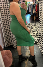Load image into Gallery viewer, Full-body side view of a size 14 Pretty Little Thing kelly green asymmetrical high, high slit sexy midi dress styled with black combat boots on a size 14/16 model.
