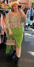 Load image into Gallery viewer, Full-body front view of a size 20 Eloquii bright lime green mini-maxi skirt with ruching and a high-low tulip hem styled with a ruffled blouse, cream beret, and gold purse on a size 22/24 model.

