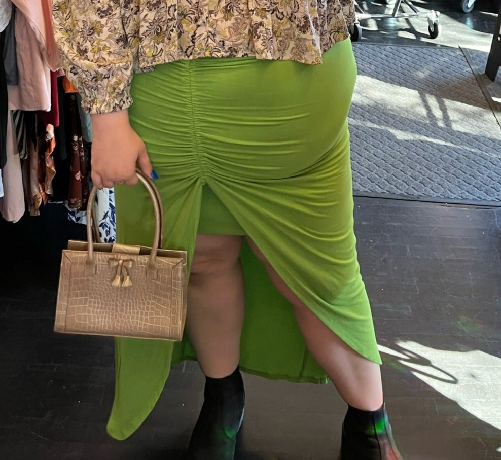Close up front view of a size 20 Eloquii bright lime green mini-maxi skirt with ruching and a high-low tulip hem on a size 22/24 model.