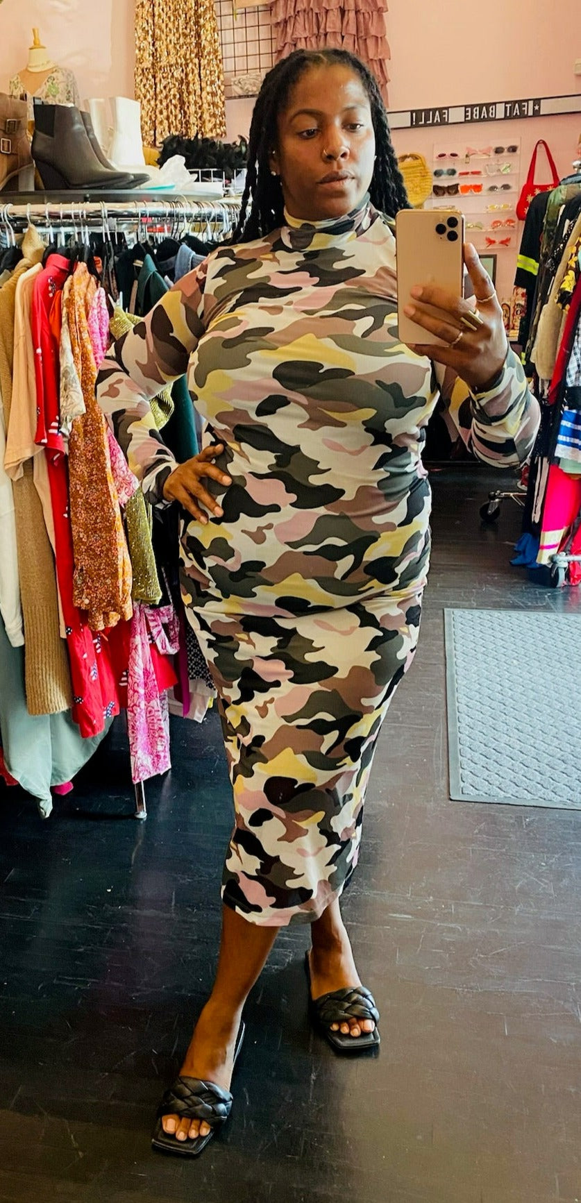 Full-body front view of a size XL Hugo green, yellow, and tan camo long sleeve mockneck bodycon maxi dress styled with black slides on a size 14/16 model.