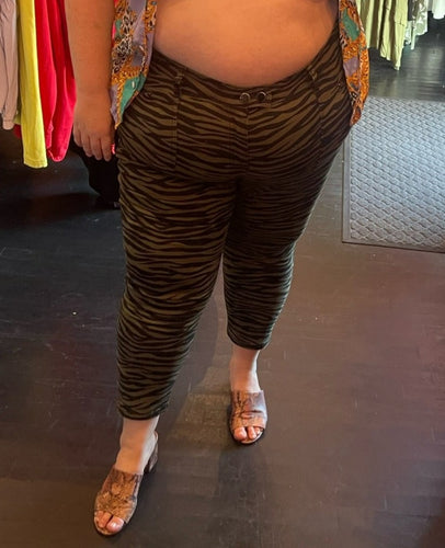Front view of a pair of size 26P Lane Bryant olive green and black zebra stripe tapered pants with zipper pocket details on a size 24 model.