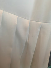 Load image into Gallery viewer, Slightly zoomed out view of a small pull in one of the pleats of a size 16 Jamie Wei Huang white asymmetrical hem midi dress with pleated skirt, pocket details, and faux leather straps.
